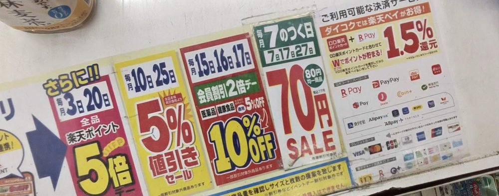 ダイコクドラッグのレジ台の案内。毎月のおトクな日と、使える決済サービスの一覧(楽天ペイとDD楽天ポイントカードで1.5%還元)
