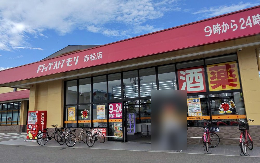 ドラッグストアモリ赤松店の外観。赤い看板に「ドラッグストアモリ 赤松店」「9時から24時」、窓に「酒」「薬」の文字