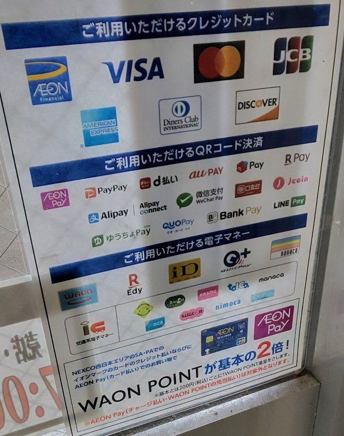 桜島SAの入口の掲示。ご利用いただけるクレジットカード7ブランド、QRコード決済、電子マネーのマークと、「NEXCO西日本エリアのSA・PAでのイオンマークのクレジットカード払いならびにAEON Pay（カード払い）でのお買い物でWAON POINTが基本の2倍」の案内